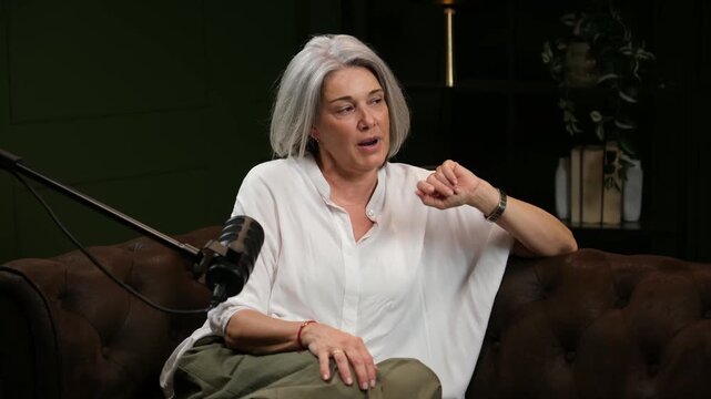 Expressive senior woman with silver hair talking and gesticulating during a live stream