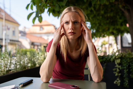 Overheated Vacationer: A woman feeling the heat of the sun on a vacation, holding her head in distress.