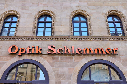 German optician store facade with Optik Schlemmer sign on a historic stone building with elegant arched windows, European local healthcare business and retail concept.