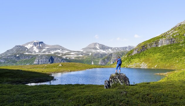 Female hiker standing on a rock in front of a mountain landscape, small lake in the Flatvaddalen high valley, side valley of Innerdalen, Sunndal, M&oslash;re og Romsdal, Vestlandet, Norway