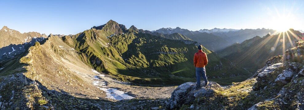 Mountaineer in front of mountain landscape at sunrise, sun star, view of mountain peaks of the Venediger group and into the Gro&szlig;bachtal valley from the summit of Bachlenkenkopf, Las&ouml;rling group, Hohe Tauern National Park, East Tyrol, Tyrol, Austria