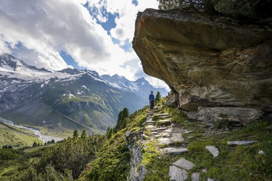Mountaineer barefoot on a hiking trail under a rocky outcrop, mountain landscape with Waxeggkees, Berliner H&ouml;henweg, Zillertal Alps, Zillertal, Tyrol, Austria