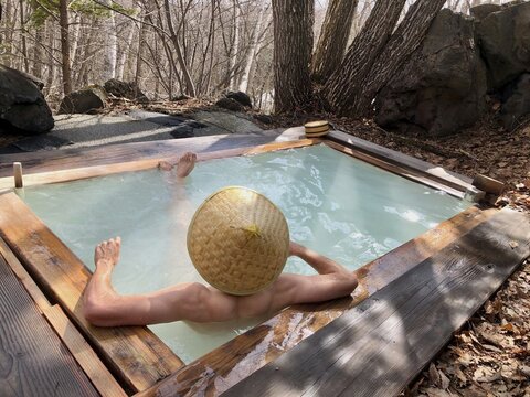 Young man with Japanese hat bathes in an onsen, hot spring of a guesthouse, Matsumoto, Japan