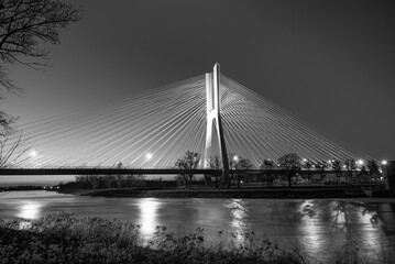 Fototapeta premium Black-and-white photo of a cable-stayed bridge illuminated in the evening.
