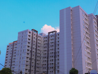 Fototapeta premium Modern apartment building rises against a clear blue sky during the golden hour of the late afternoon.