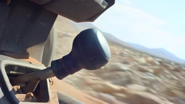 Hand shifting gear close-up during rocky off-road climb, built for difficult terrain control, manual driving skill, vehicle traction, adventure transport, rugged travel, and mechanical reliability ads