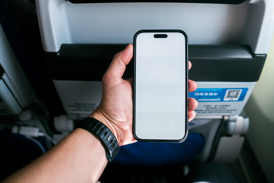 A man uses a mobile phone with white screen on an airplane