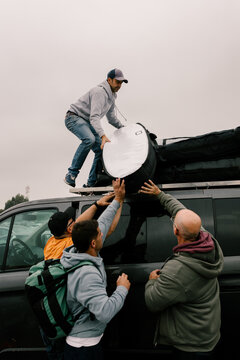 Group of friends fastening surfboards to the roof of a van in Morocco