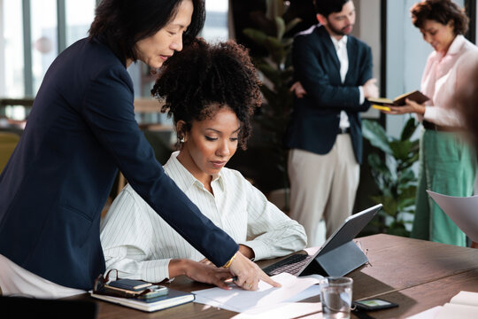 Businesswomen collaborate on a project at a modern office.