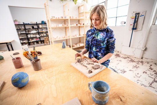 Teen Working with Clay at Worktable in Bright Ceramics Studio