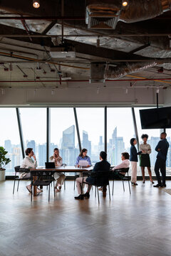 Diverse team meeting in modern office with city view.