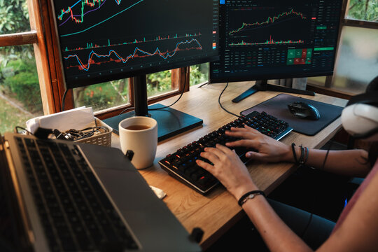 Trader hands working with Stock chart on Multiple Screens