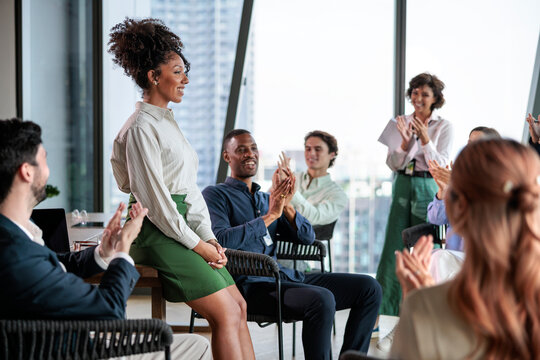 Team applauding colleague during office meeting