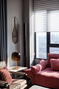 Sunlit modern interior with pink sofa, lamp, and window.