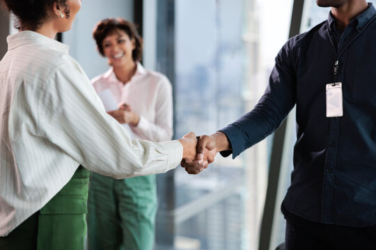Business handshake with smiling colleague in modern office setting.