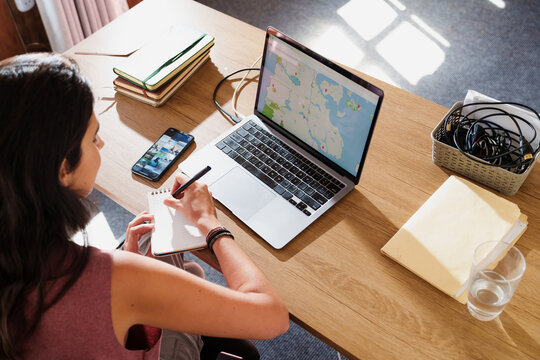Woman Planning a Trip with Laptop and Smartphone at Home