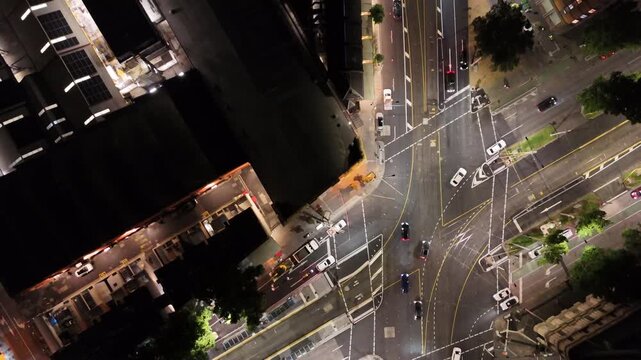 Cinematic top-down drone footage of illuminated streets and moving traffic in Melbourne at night. A geometric aerial perspective showcasing urban infrastructure, road markings and modern city life.