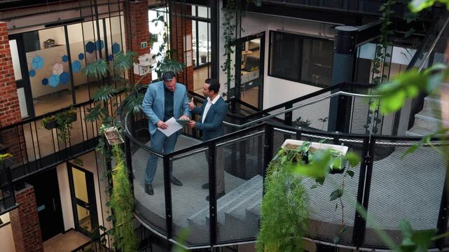 People, discussion and tablet in office with sustainable business, planning or research for project. Men, tech and conversation on stairs for eco friendly goals, environmentalist advice and above.