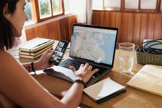 Woman Planning a Trip with Laptop and Smartphone at Home
