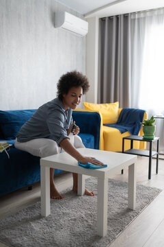Cheerful black woman washing table