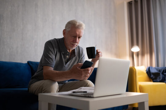 Senior man with cup using smartphone