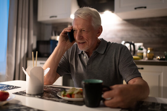 Senior man speaking on smartphone during dinner