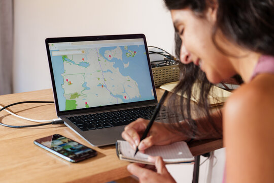 Woman Planning a Trip with Laptop and Smartphone at Home