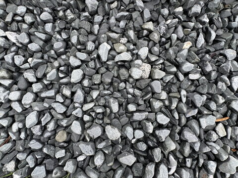 Full frame texture of dark grey crushed gravel stones. Small black and charcoal pebbles on the ground for rustic garden landscaping, modern abstract mineral rock background.