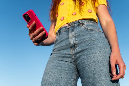 Woman Holds Phone Under Clear Blue Sky 