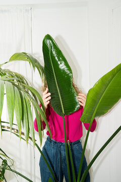 Woman caring for houseplants on a sunny balcony in bright colors