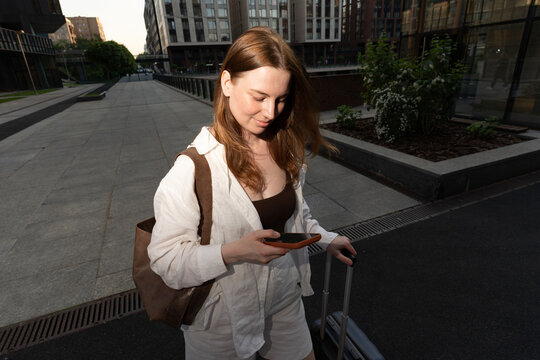 Reading a message while pulling luggage through the city