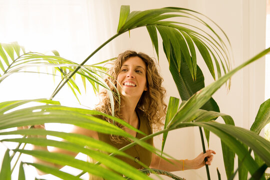 Woman enjoys plants in a bright balcony garden space