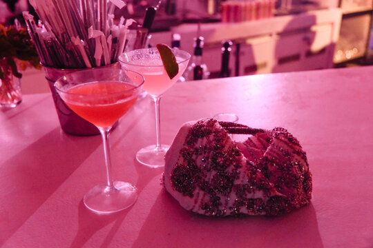 Cocktails and a Decorative Purse on a Bar Counter at Night