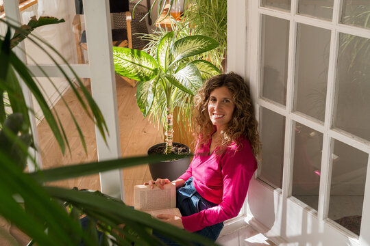 Woman enjoying a book on the balcony surrounded by houseplants