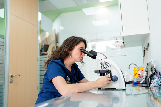 Veterinarian woman analyzing samples using a microscope