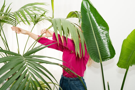 Woman caring for houseplants on a sunny balcony in bright colors