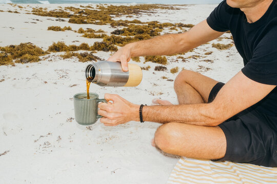 Man Pouring Coffee Into Mug on Gulf Coast Beach
