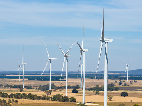 Tall wind turbines on dry countryside against a blue sky