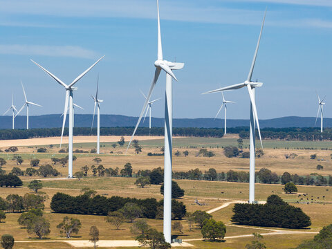 Tall wind turbines on dry countryside against a blue sky