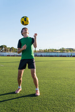 Teen boy training soccer skills juggling ball on head