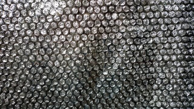 A high-resolution 4K looping animation featuring a shimmering, shiny silver metallic foil bubble wrap texture.