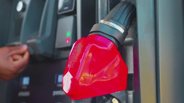 Red gas pump nozzle handle at service station dispenser