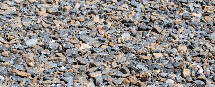 Crushed stone gravel texture small rocks grey pebble surface background for construction panoramic copy space design	

