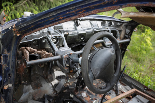 Detail of damaged interior, dashboard and steering wheel. Abandoned old rusty and corroded wreckage, wreck, auto, automobile, car and vehicle. Dismantled scrap and junk. Shallow focus.