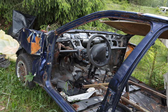 Detail of damaged interior, dashboard and steering wheel. Abandoned old rusty and corroded wreckage, wreck, auto, automobile, car and vehicle. Dismantled scrap and junk. Scrapyard and junkyard in natu