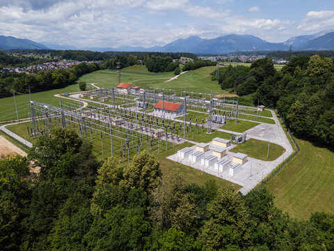Aerial view of a Battery Energy Storage System and power substation surrounded by green fields and forests in Slovenia.