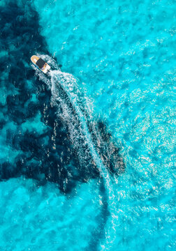 Aerial drone view of floating speed boat in blue sea on sunny day. Summer vacation. Mallorca island, Spain. Top down view of boat, sea, turquoise water. Travel. Tropical landscape. Yachting. Cruise