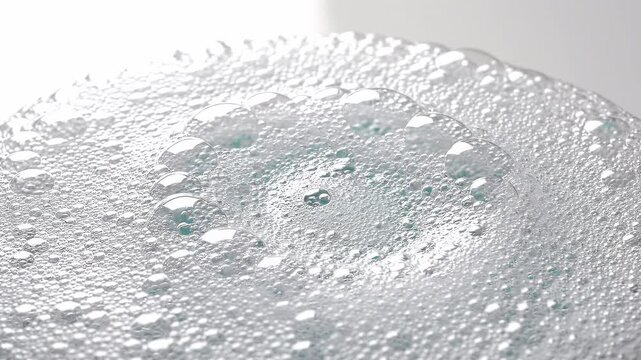 Close-up macro shot of transparent soap bubbles and foam on a white surface with soft, diffused lighting
