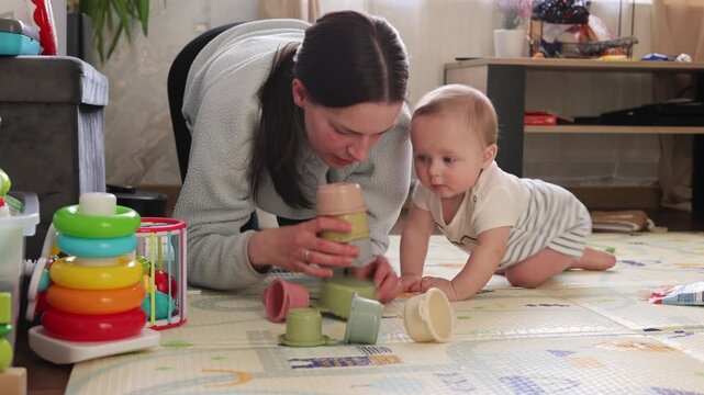 Child Explores Toys With Attentive Mother Nearby. Warm Home Setting Fosters Early Learning As Mother And Baby Engage With Colorful Toys And Bonding Moments