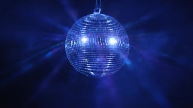 Rotating Disco Ball Reflecting Bright Blue Light Beams in Dark Nightclub Setting.